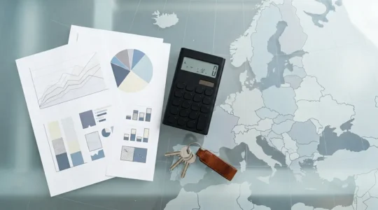 Vue plongeante d'un bureau moderne avec documents fiscaux, calculatrice et clés sur une carte de l'Europe