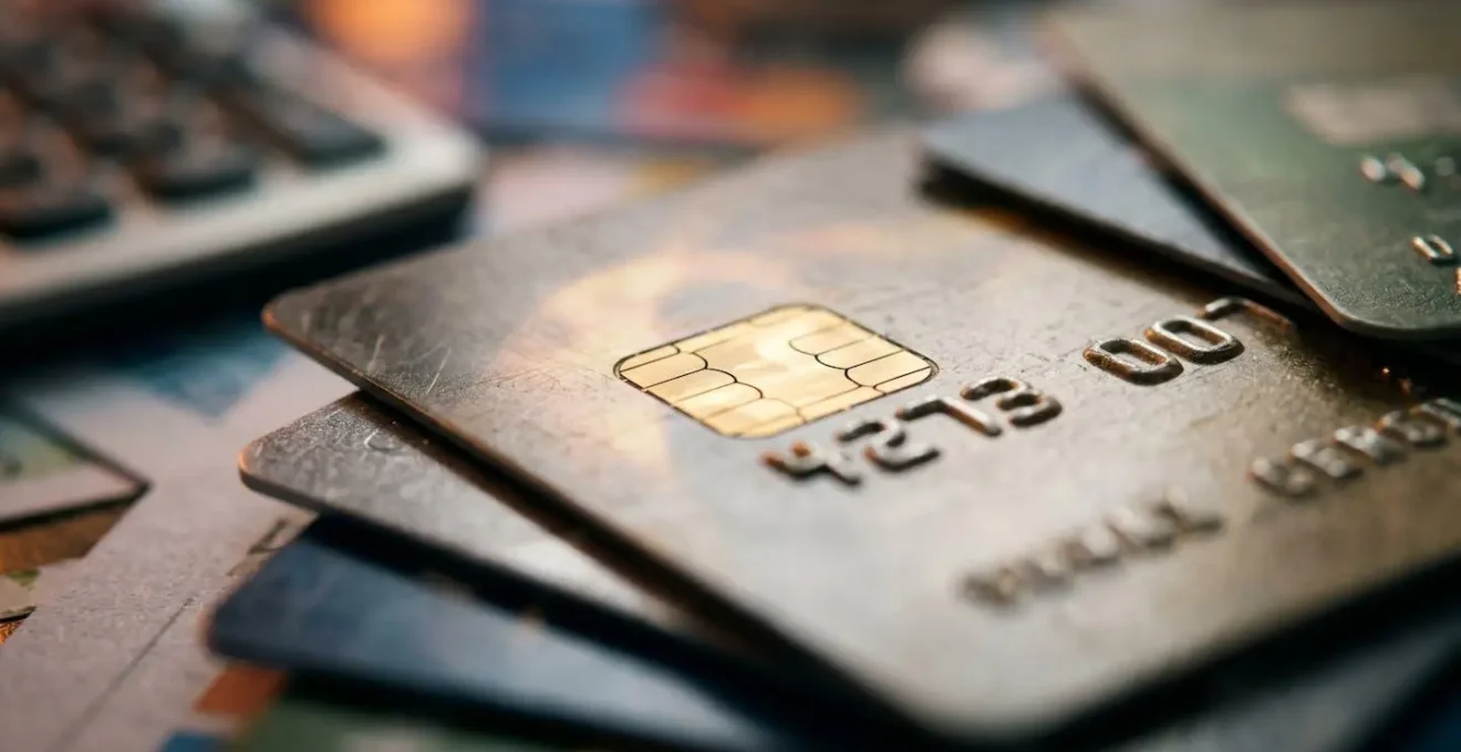 Vue macro de cartes bancaires empilées avec calculatrice floue en arrière-plan