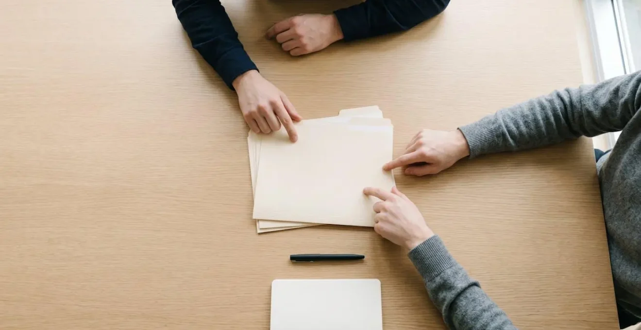 Vue aérienne d'une table de réunion avec documents juridiques et mains en discussion
