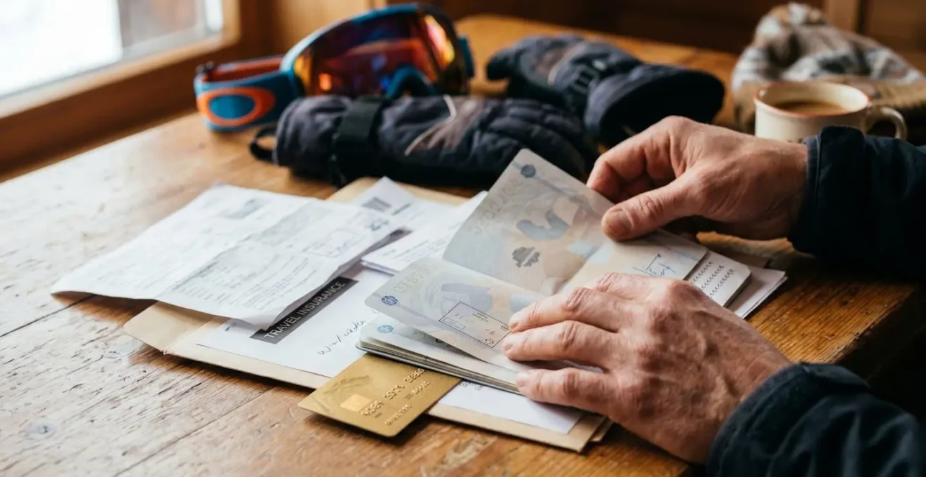 Documents d'assurance et carte Gold disposés sur table en bois avec équipement de ski en arrière-plan