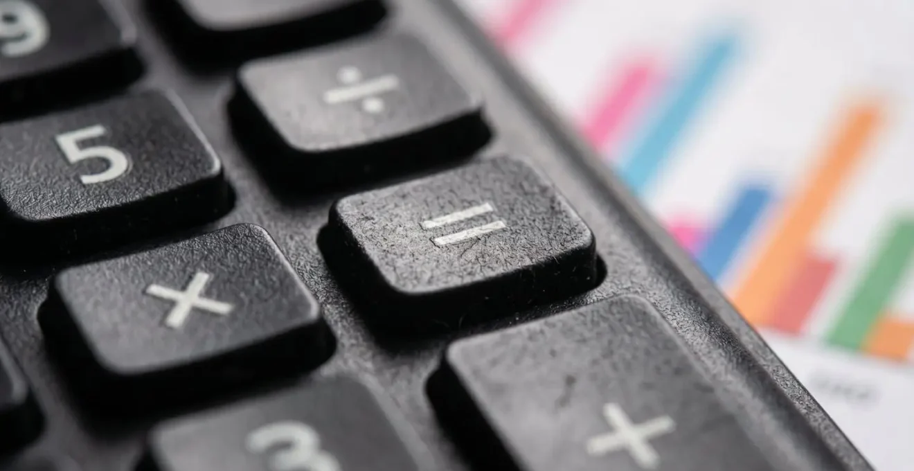 Vue macro d'une calculatrice avec graphiques financiers flous en arrière-plan